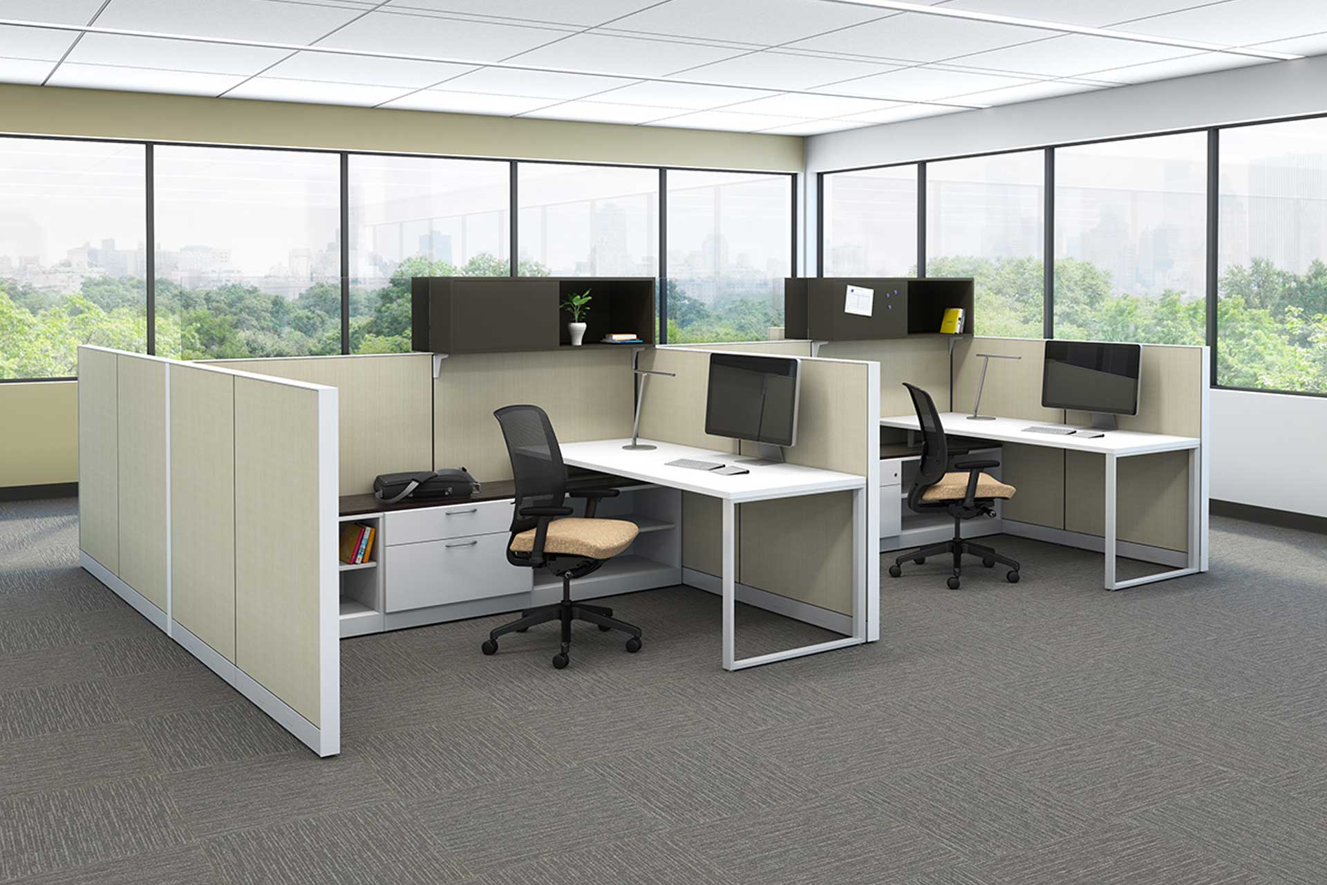 Interior view of an office with two cubicles each with a swivel chair, desk, overhead cabinets, and computer monitor,