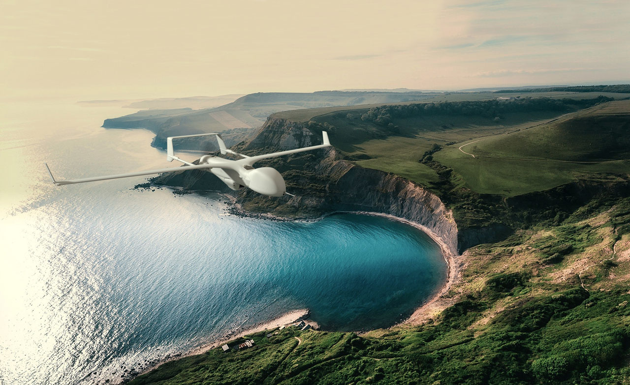 Gray Insitu Drone flying over a beach between a blue ocean and lush green hills